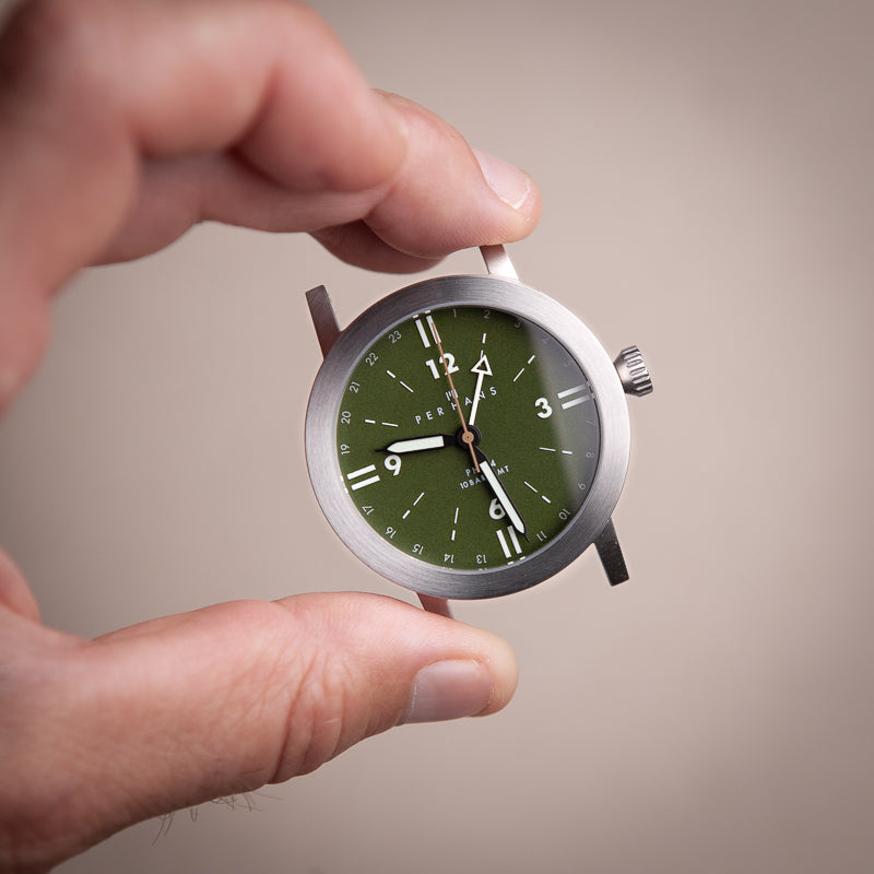 Hand holding a green dial watch case