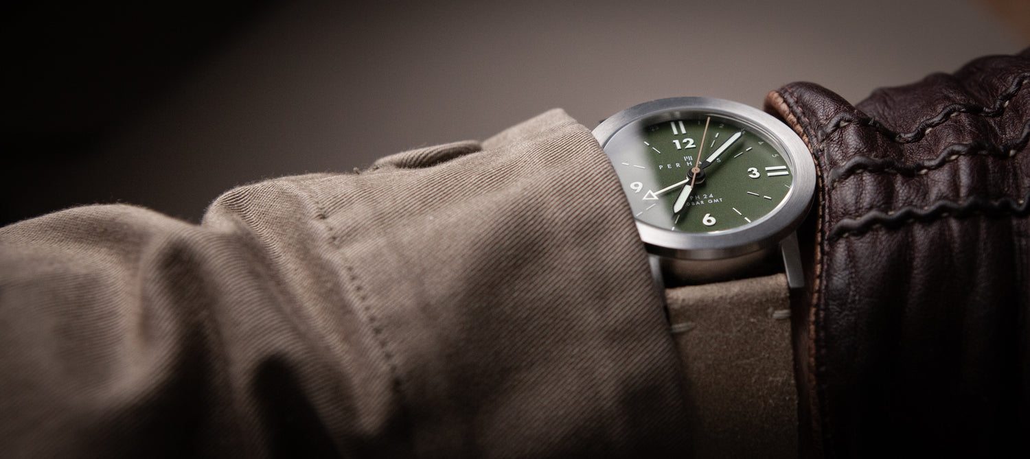 Arm with a green dial watch with a suede leather strap