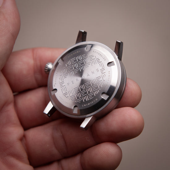 Hand holding a watch upside down. Steel case back visible