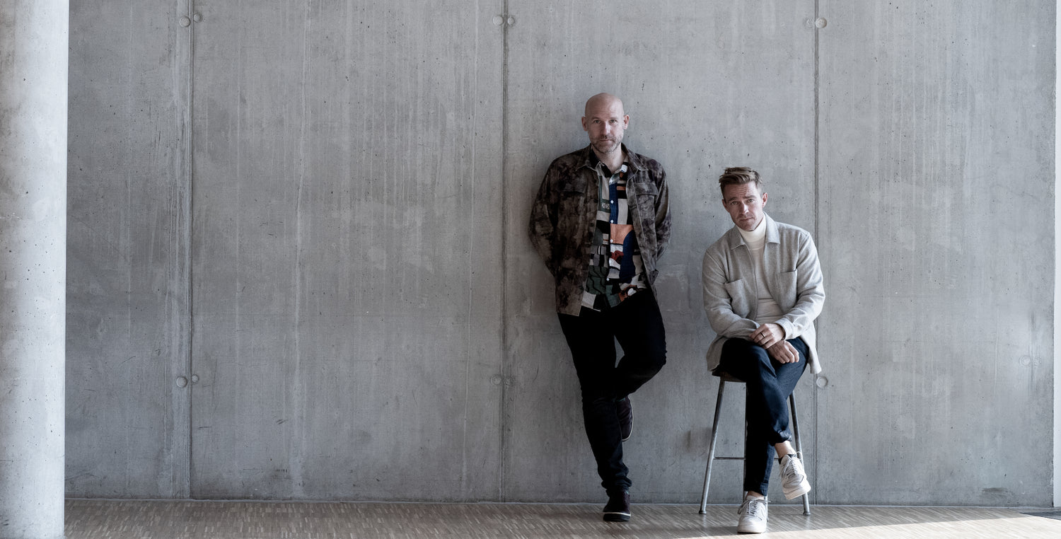 The two founders of Per Hans posing up against a concrete wall